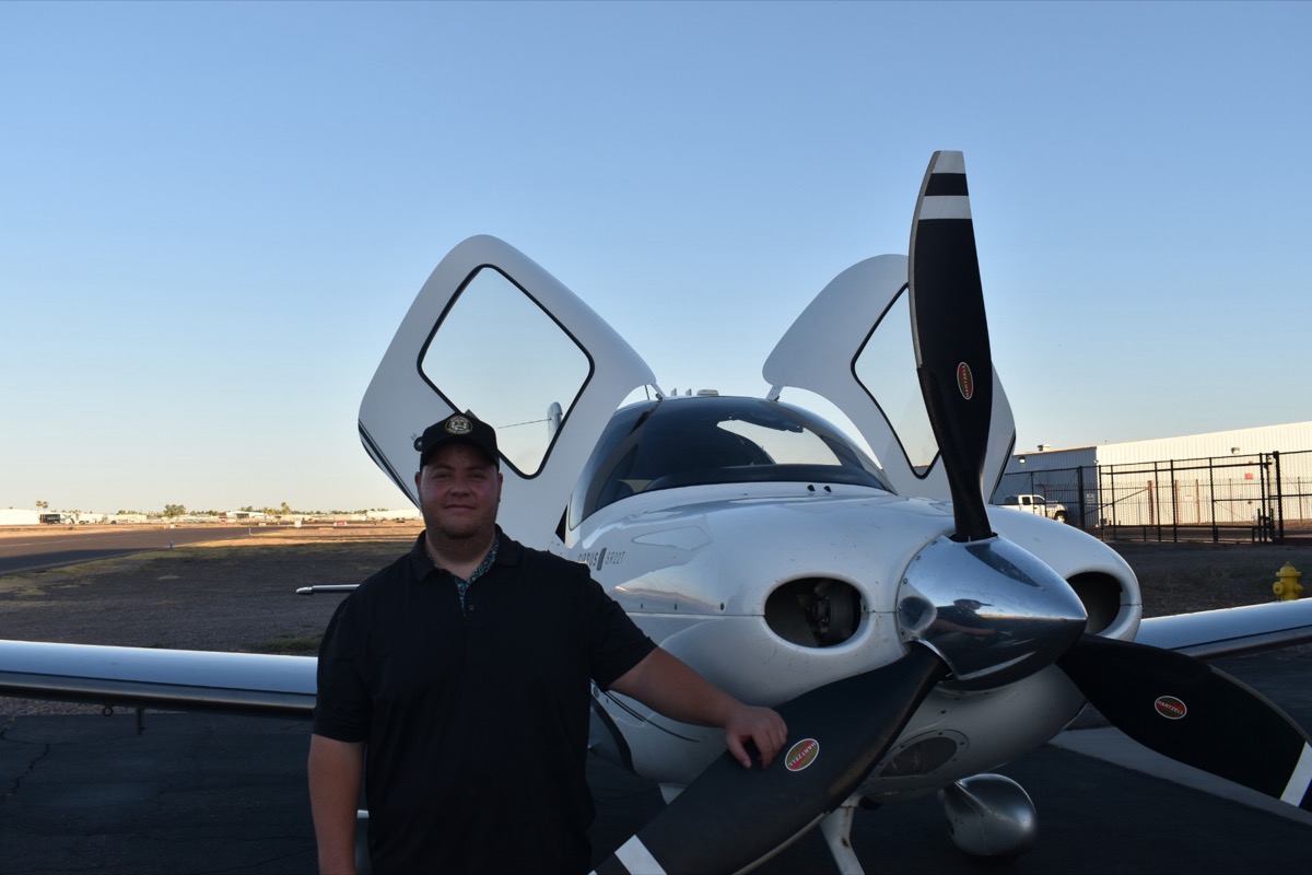 Easton Harrison, CFI standing next to a Cirrus SR207